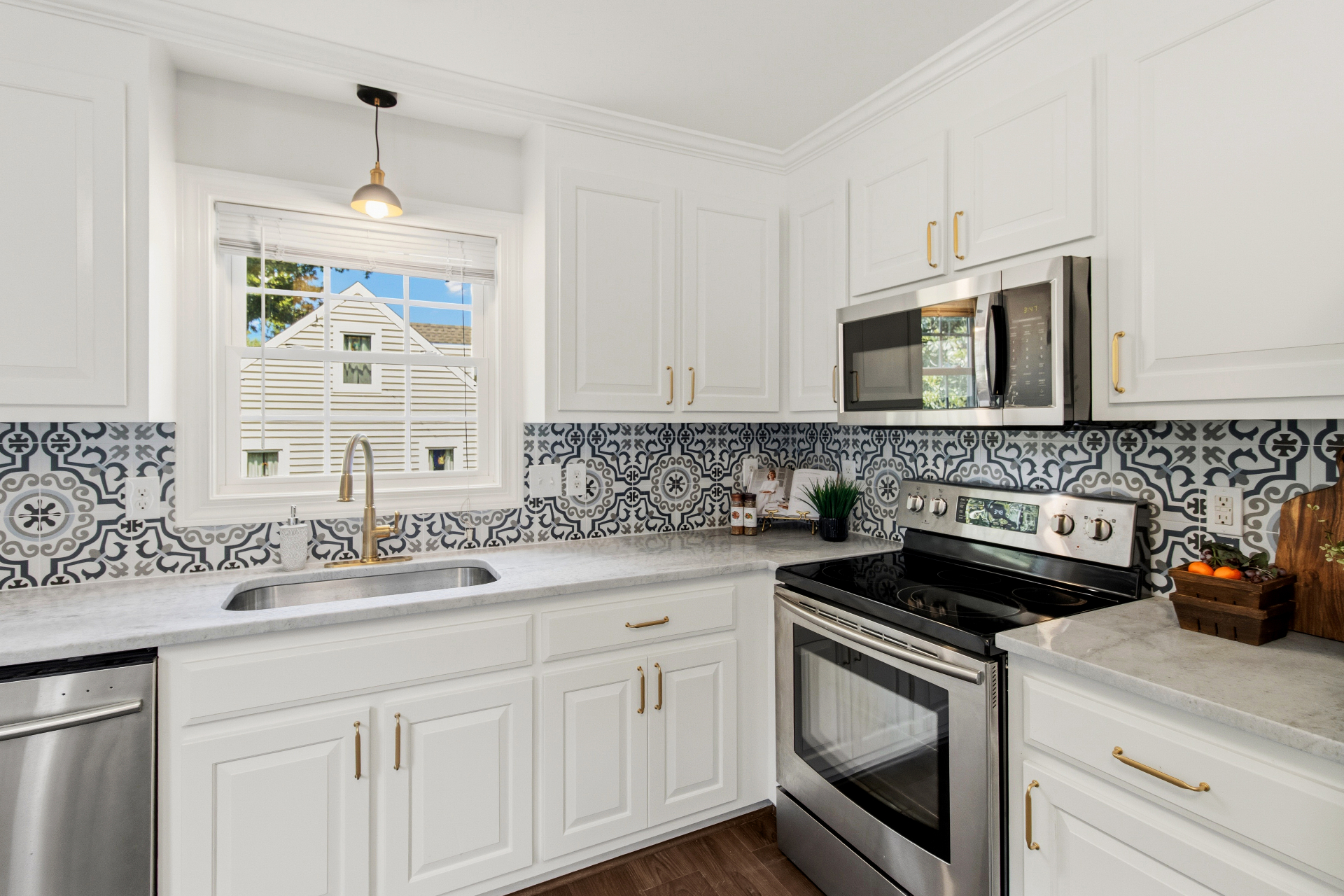 White kitchen with brass hardware, stainless appliances, and patterned tile backsplash