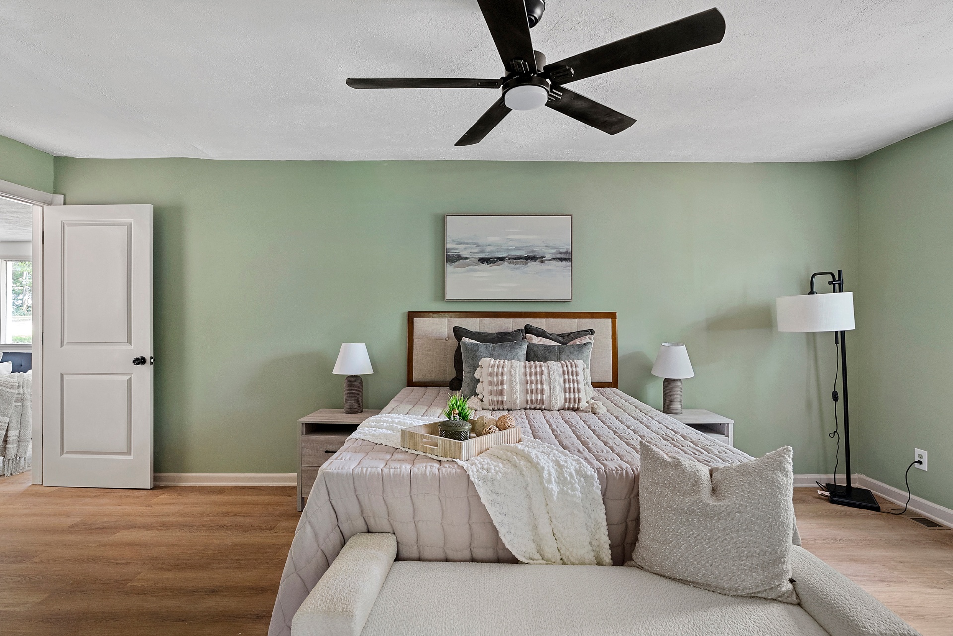 Staged primary bedroom with sage accent wall