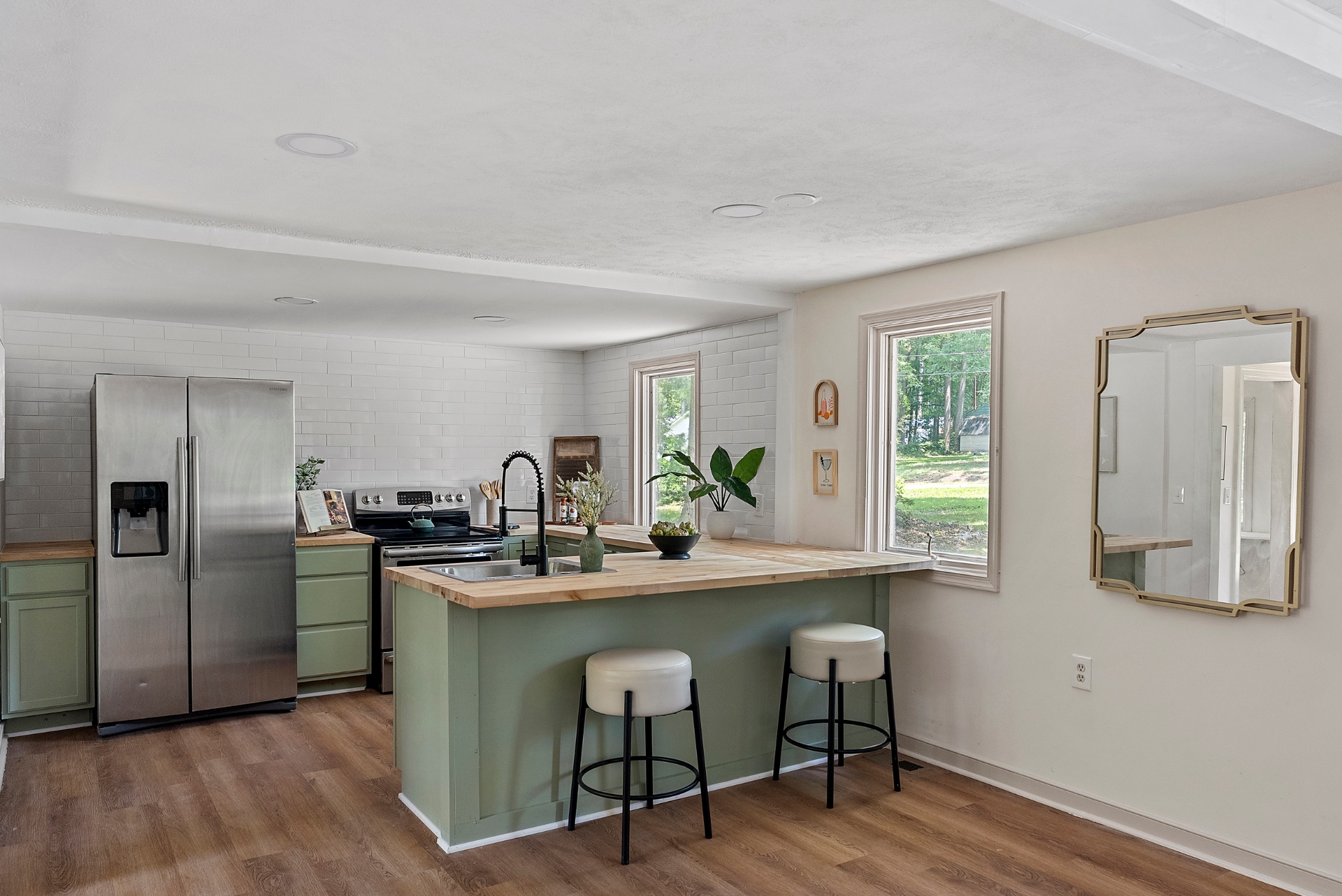 Bright open kitchen with sage cabinets and natural light